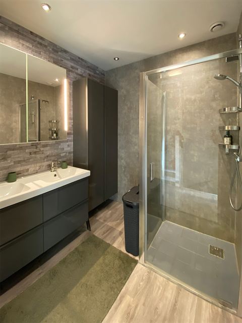 Badkamer met douche, dubbele wastafel en opbergruimte.