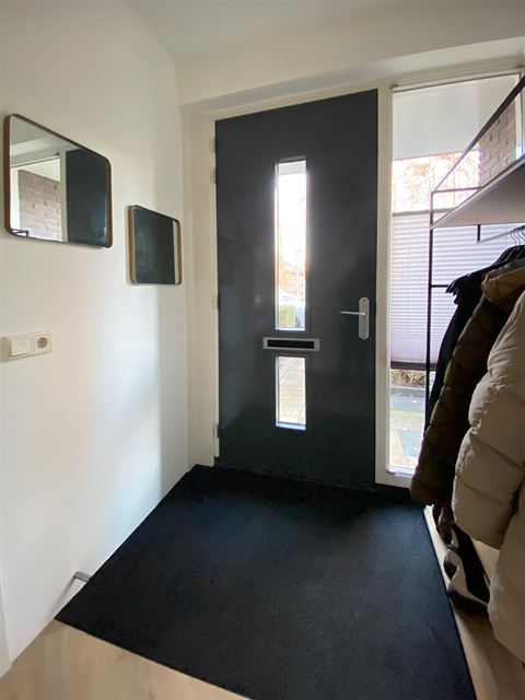Zicht vanuit de hal op de voordeur en garderobe.