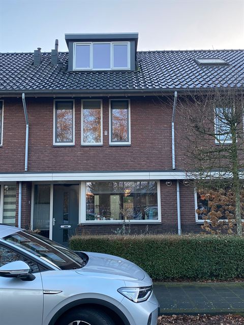 Voorgevel met dakkapel, met een geparkeerde auto op de voorgrond.