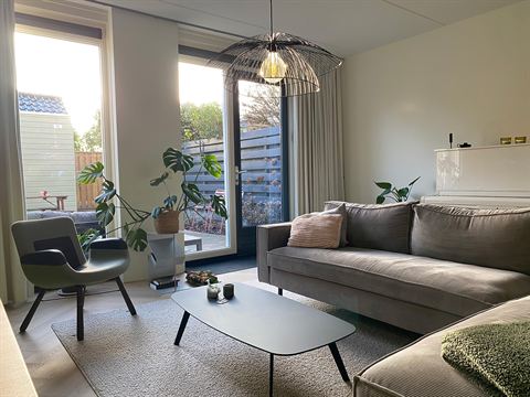 Lichte woonkamer met een deur naar de tuin.