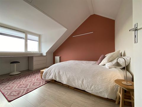 Ruime slaapkamer op zolder met bed en daglicht vanuit de dakkapel.